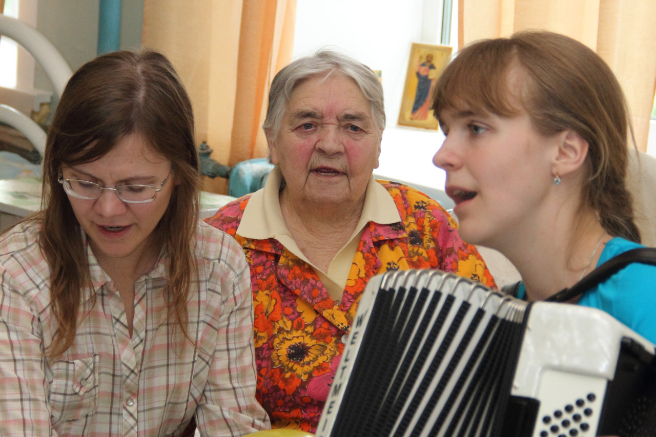 Волонтеры поют песни в палатах вместе со стариками, которые не могут выйти в общий холл.