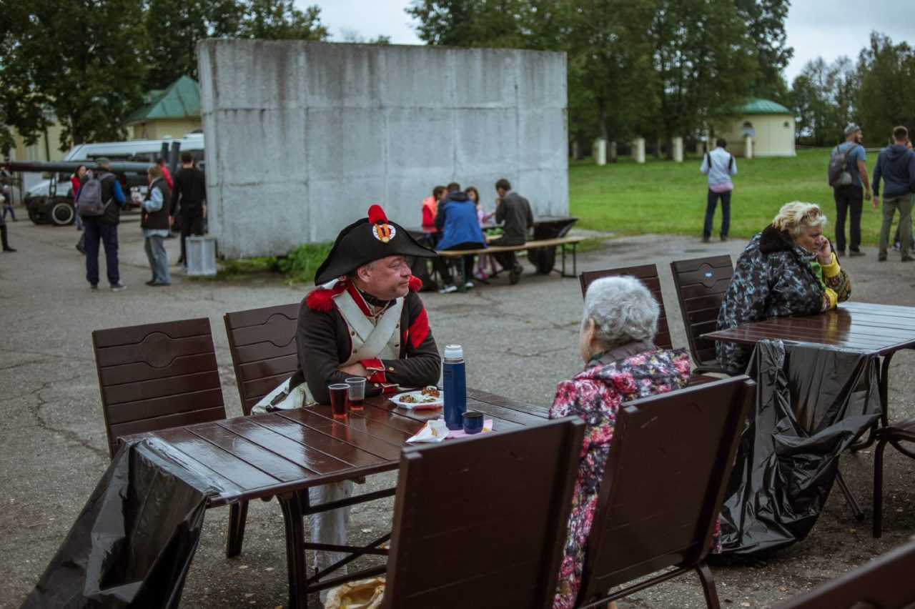 Один из реконструкторов сидит за столом кафе и завтракает.